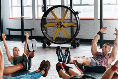 Image of a group exercising with a large portable industrial fan sitting in the background.
